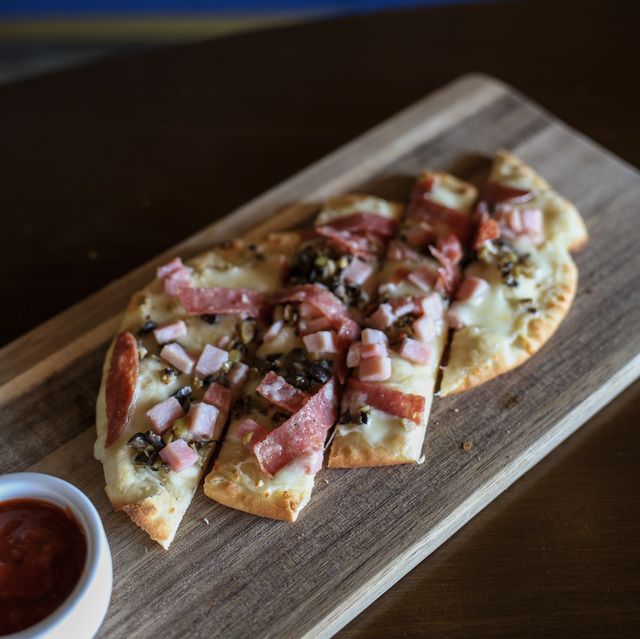 Muffuletta flatbread sliced on a wooden board