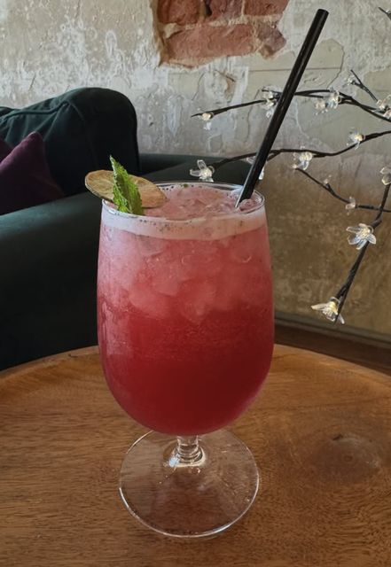 A pink mocktail with mint and lime on a round table